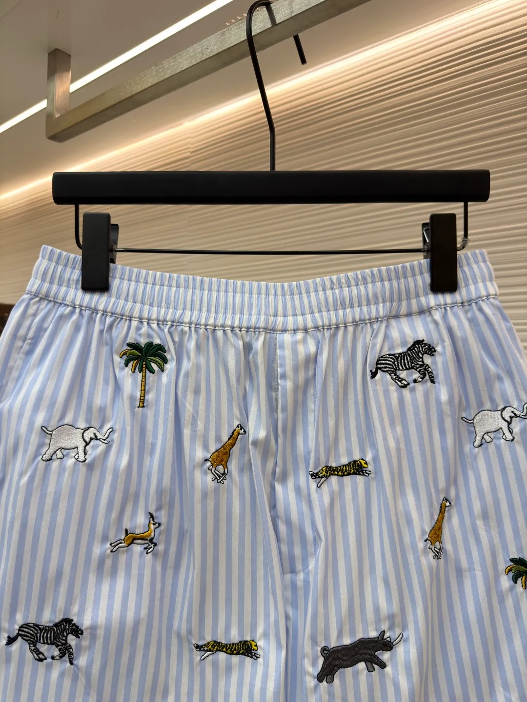 LOUIS VUITTON Animal and plant nostalgic style embroidered striped shorts ●Original version: purchased and developed by 14616 ●Item number: 1682542-A75 ●Fabric: cotton fabric ●Technology: embroidery production ●Color: blue ●Version: fitted version ●Weight: about 205 grams ●Size: S-M-L-XL ●Description: Made of high-count pure cotton poplin fabric. After pre-washing process, it feels smooth and breathable. It has both drape and stiffness, and is not easy to wrinkle and deform. The blue and white vertical stripes on the body are woven with yarn-dyed technology, and the texture is clear and does not fade. The animal and coconut tree patterns are presented with sophisticated embroidery technology. The embroidery threads are full of color and the stitches are dense. The patterns are three-dimensional and vivid, forming a rich visual hierarchy with the stripe base. The shirt has a Cuban collar style, with smooth necklines, custom mother-of-pearl buttons at the placket, and a warm texture. The overall shape is loose, the shoulder joints are straight and fine, the cuffs are cuffed with exquisite craftsmanship, custom accessories and three logos are complete, and the details are full of luxury craftsmanship. It is suitable for casual vacations and daily outings, etc. The overall wiring is straight and delicate, the fabric is comfortable and soft, and the color is consistent without color difference. It can be matched with the same style to create a fashionable look and control various occasions. Customized accessories, complete with three standards, same style for men and women!